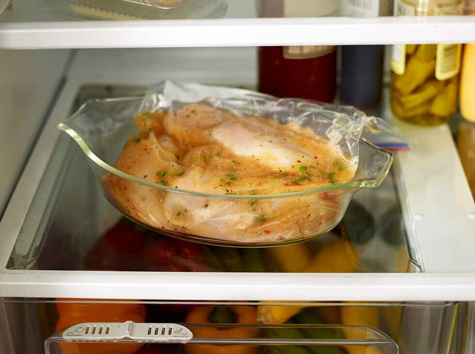 chicken marinating inside of a fridge