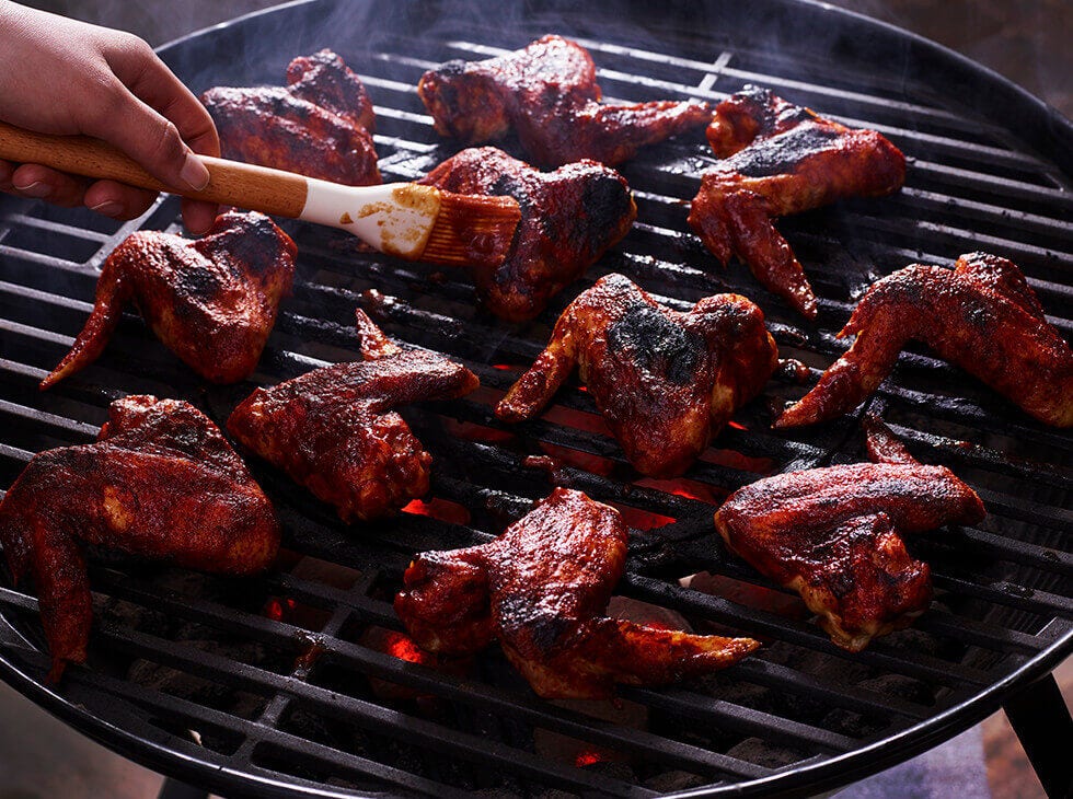 Basting chicken wings on a bbq grill