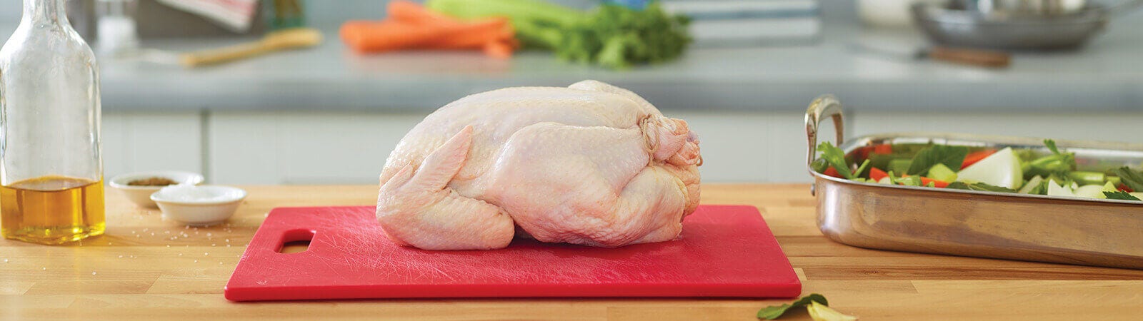 Whole raw chicken on a cutting board with a seasoning off the side