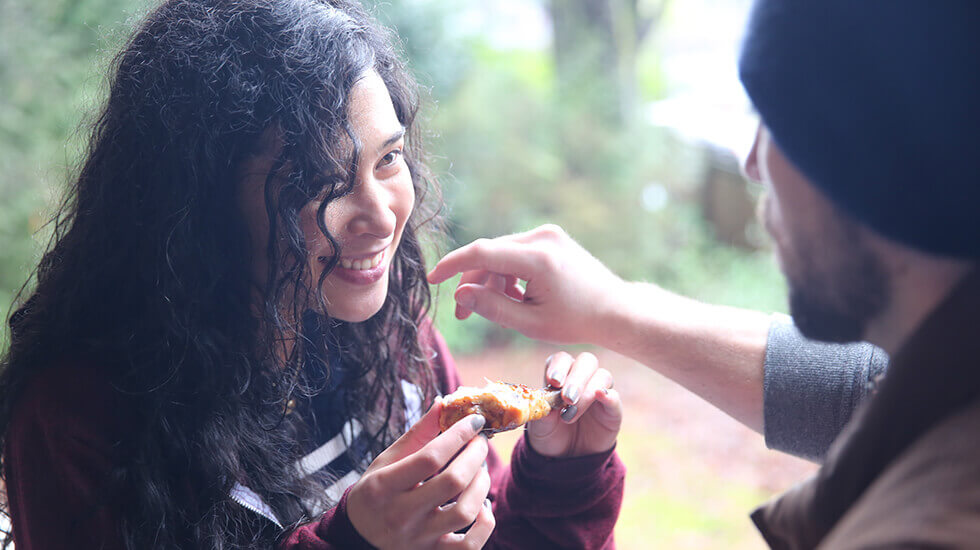 Woman eating a chicken wing and conversating with a man