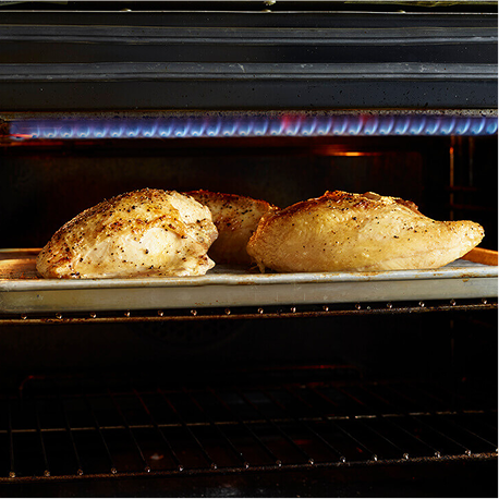 Seasoned chicken breast roasting on a sheet pan inside an oven. 