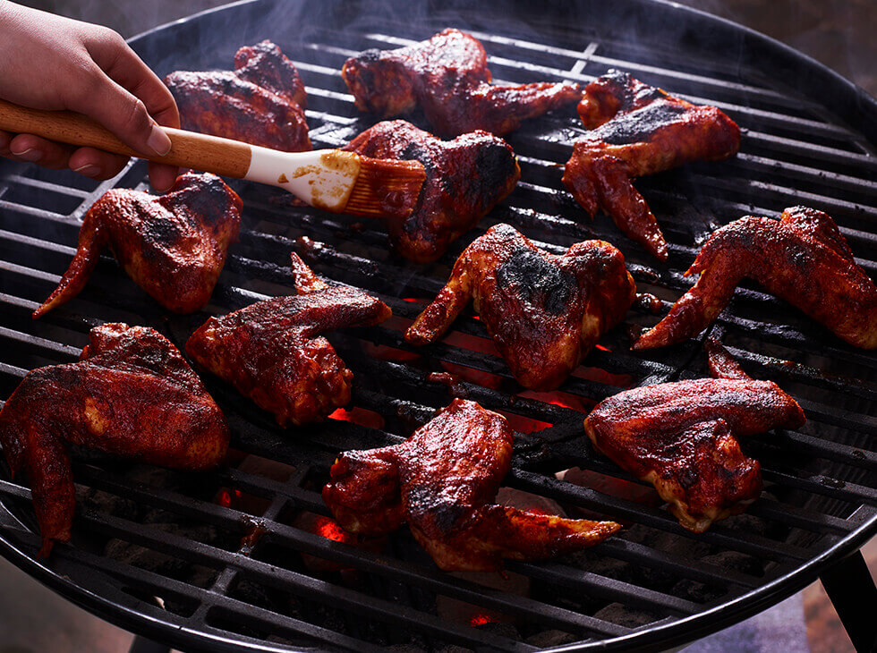 Basting chicken wings on a bbq grill
