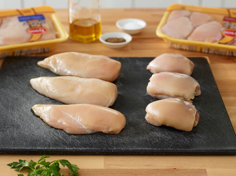 Raw chicken breasts and thighs laid out on a cutting board