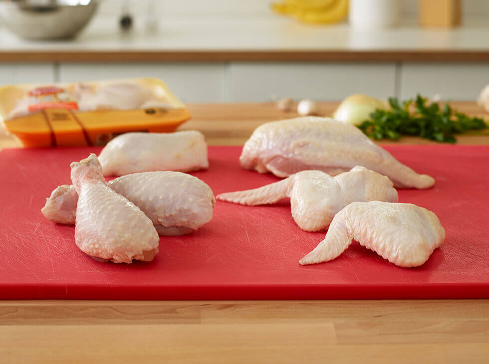 Raw chicken wings and drums laid out on a red cutting board